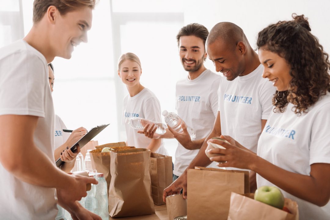 young-multiethnic-group-of-volunteers-putting-food-and-drinks-in-paper-bags-for-charity.jpg